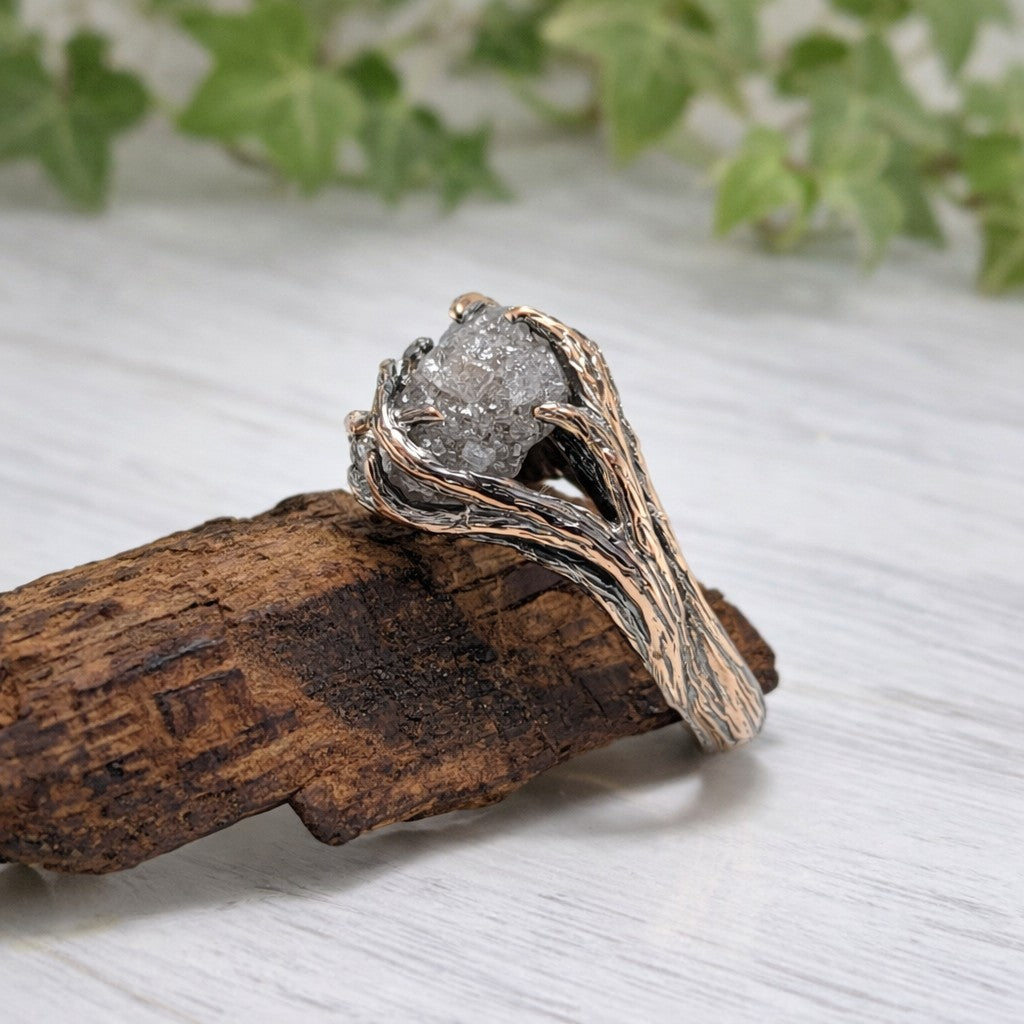 raw rough diamond twig style ring sitting on a branch shown in antiqued rose gold