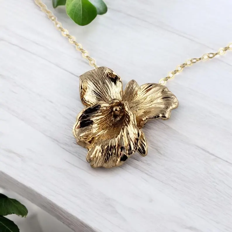 Gold flower-shaped pendant on a chain against a white background