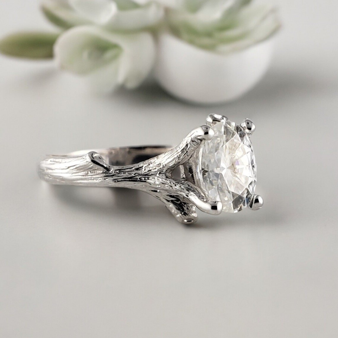 White gold twig engagement ring with an oval brilliant-cut gemstone held by branch-style prongs